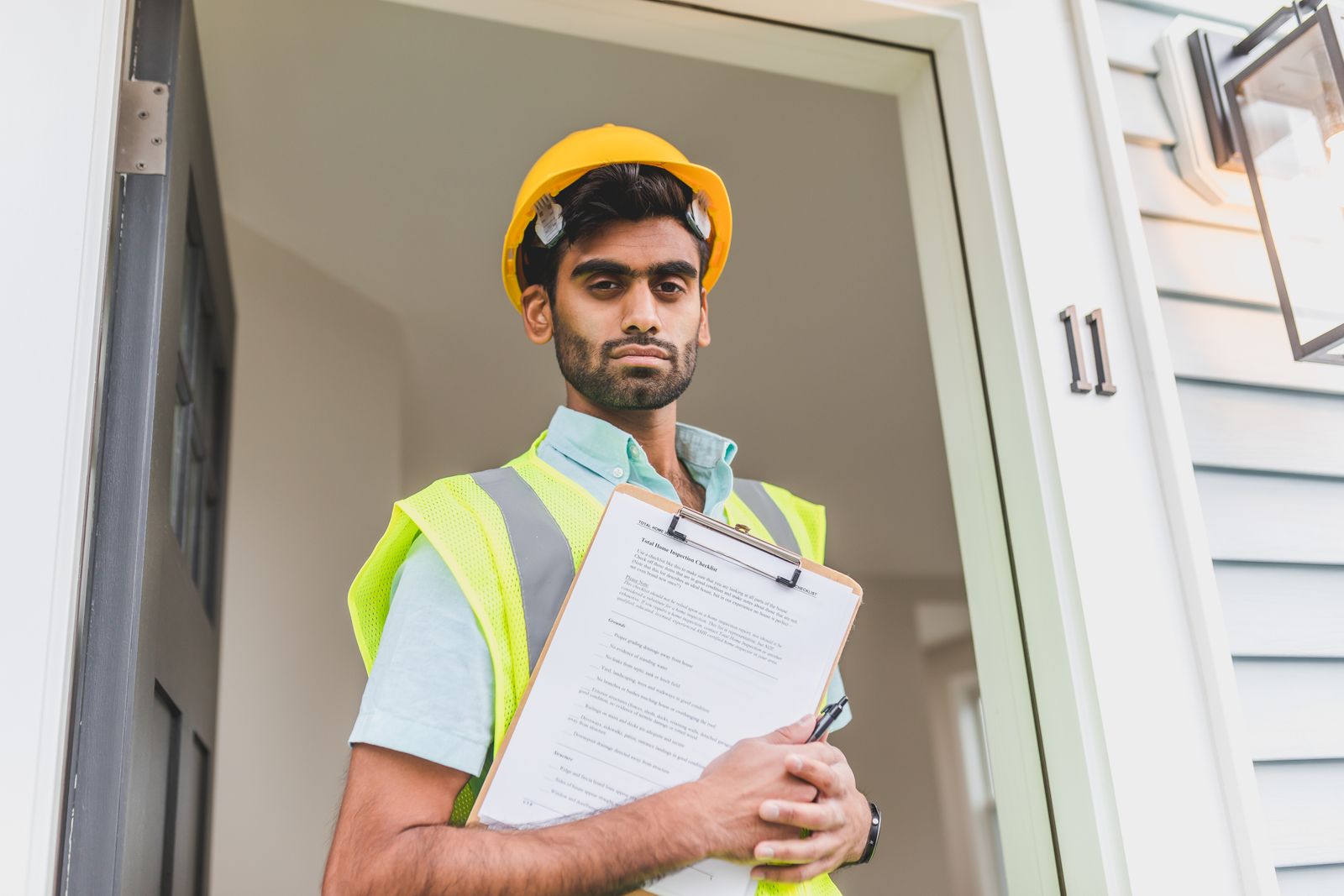 A surveyor with a home-inspection checklist at a front door