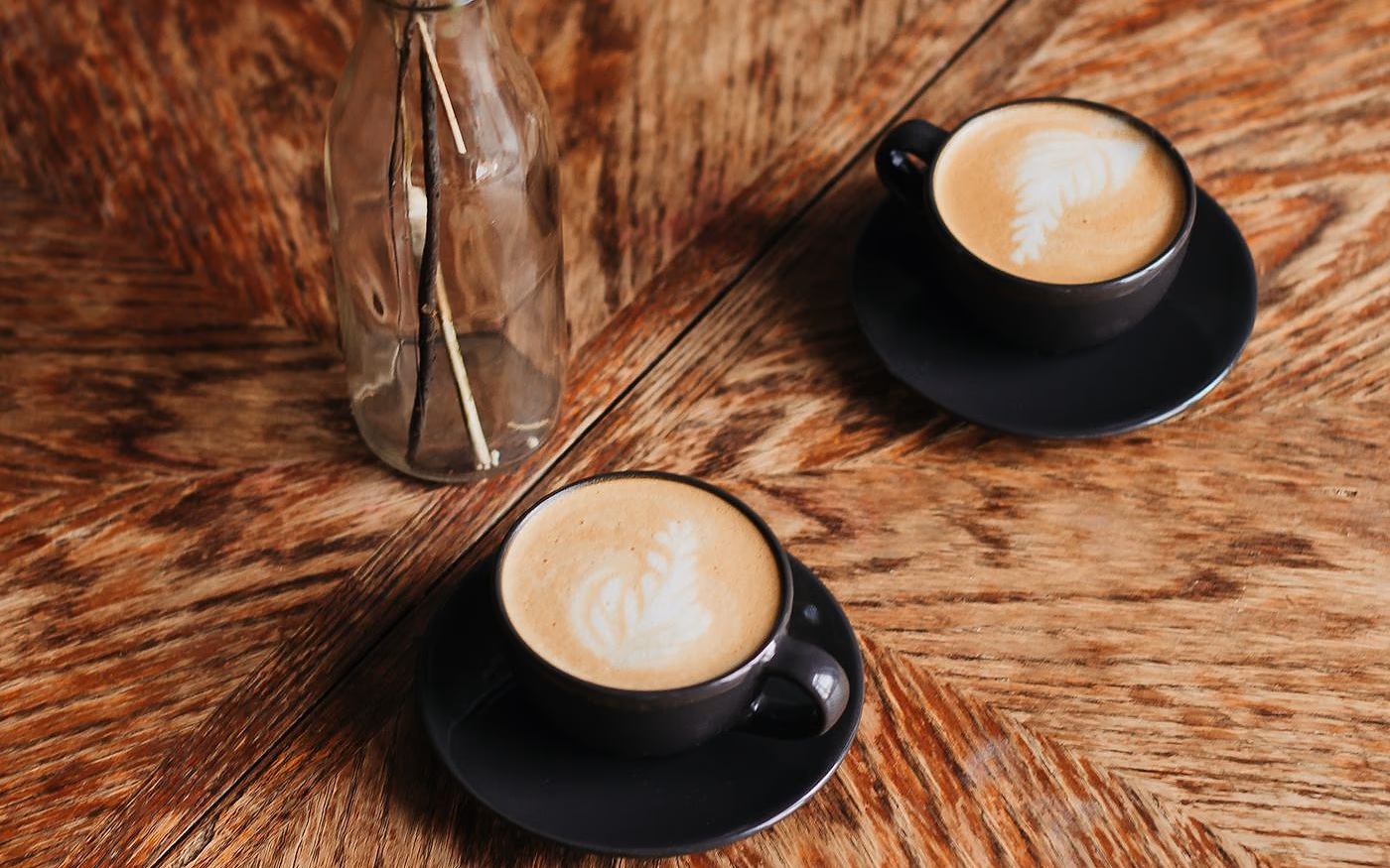 Two cups of coffee on a warm wooden table, set for a conversation