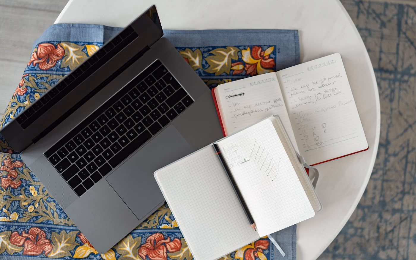 A laptop and handwritten notebooks on a table